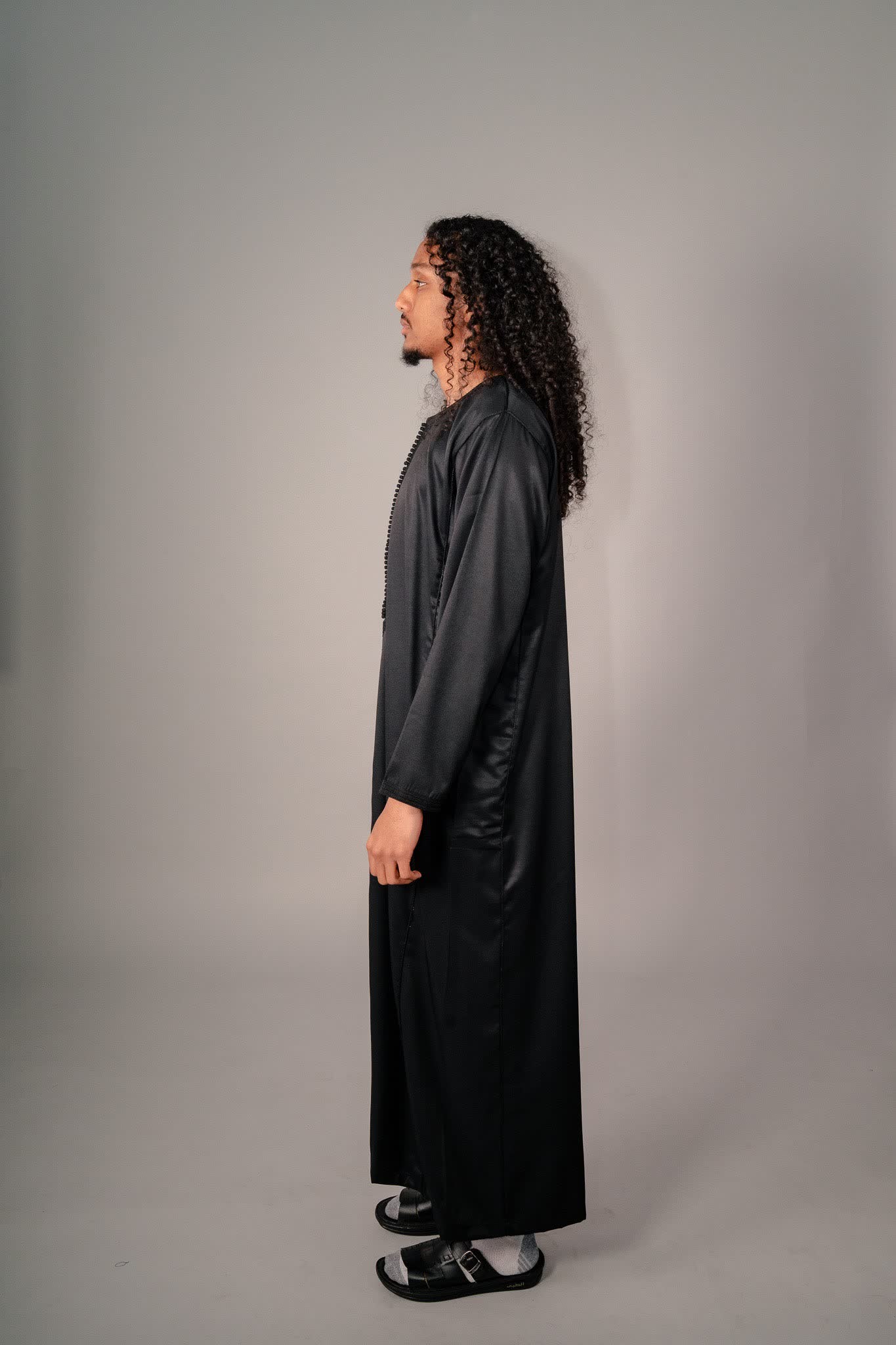 Side profile of a black Moroccan kaftan for men showing its drape