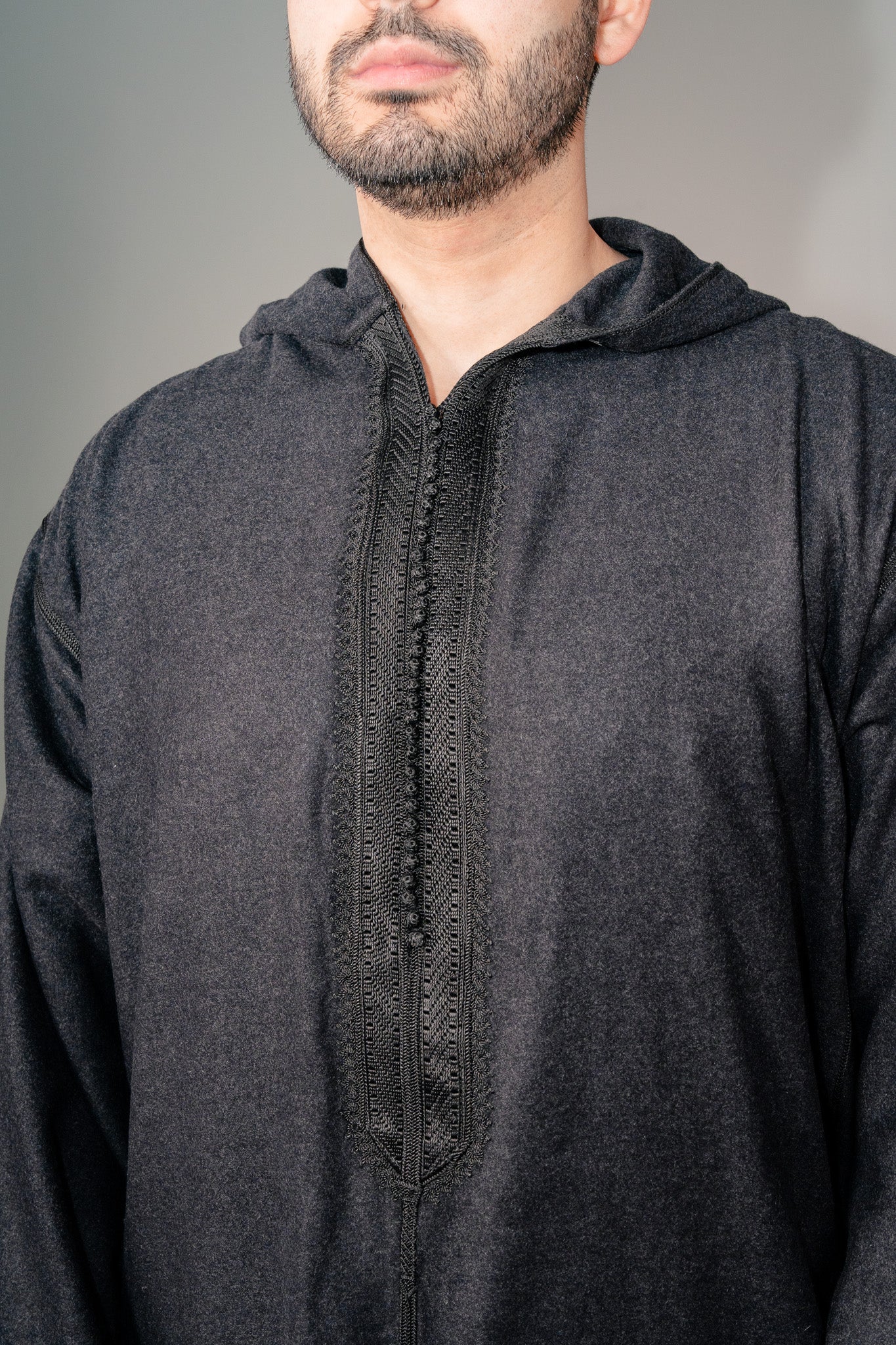 Close-up of the heavy cloth and embroidered placket on a black winter djellaba for men