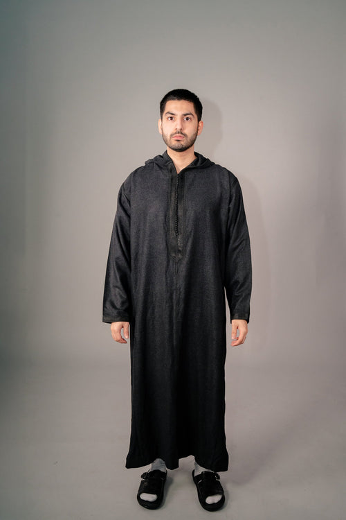 Man wearing a black Moroccan winter djellaba with the hood down, front view
