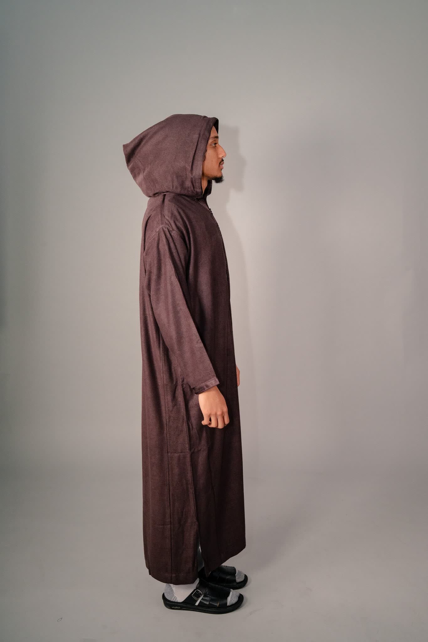 Man wearing a brown Moroccan winter djelleba, side view with the hood up