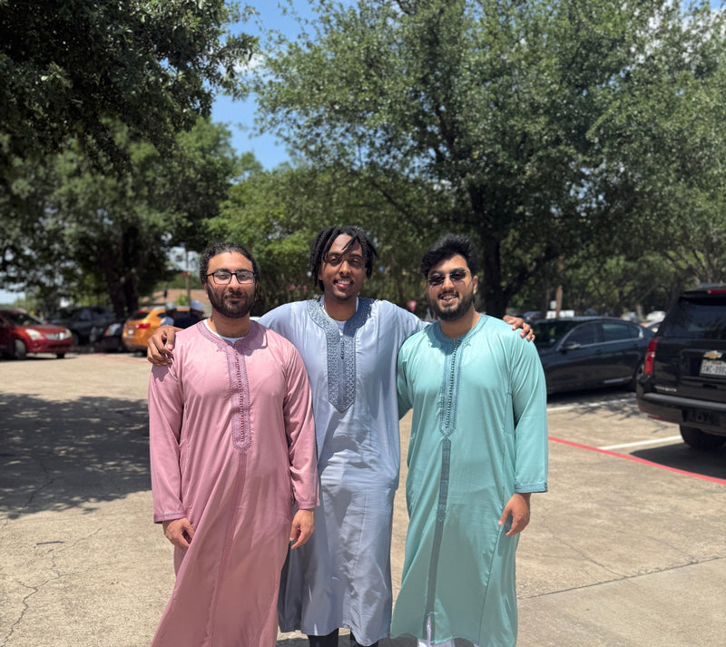 Three men outdoors in pink, pastel blue and mint Moroccan thobes