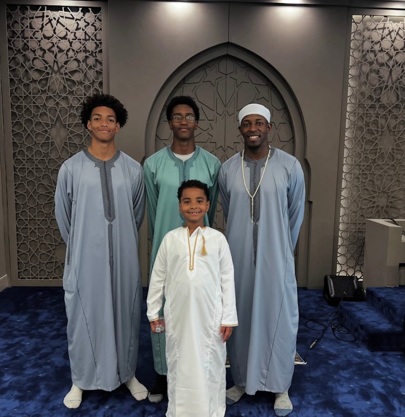 Four men and a boy inside a mosque wearing Moroccan thobes in several colours