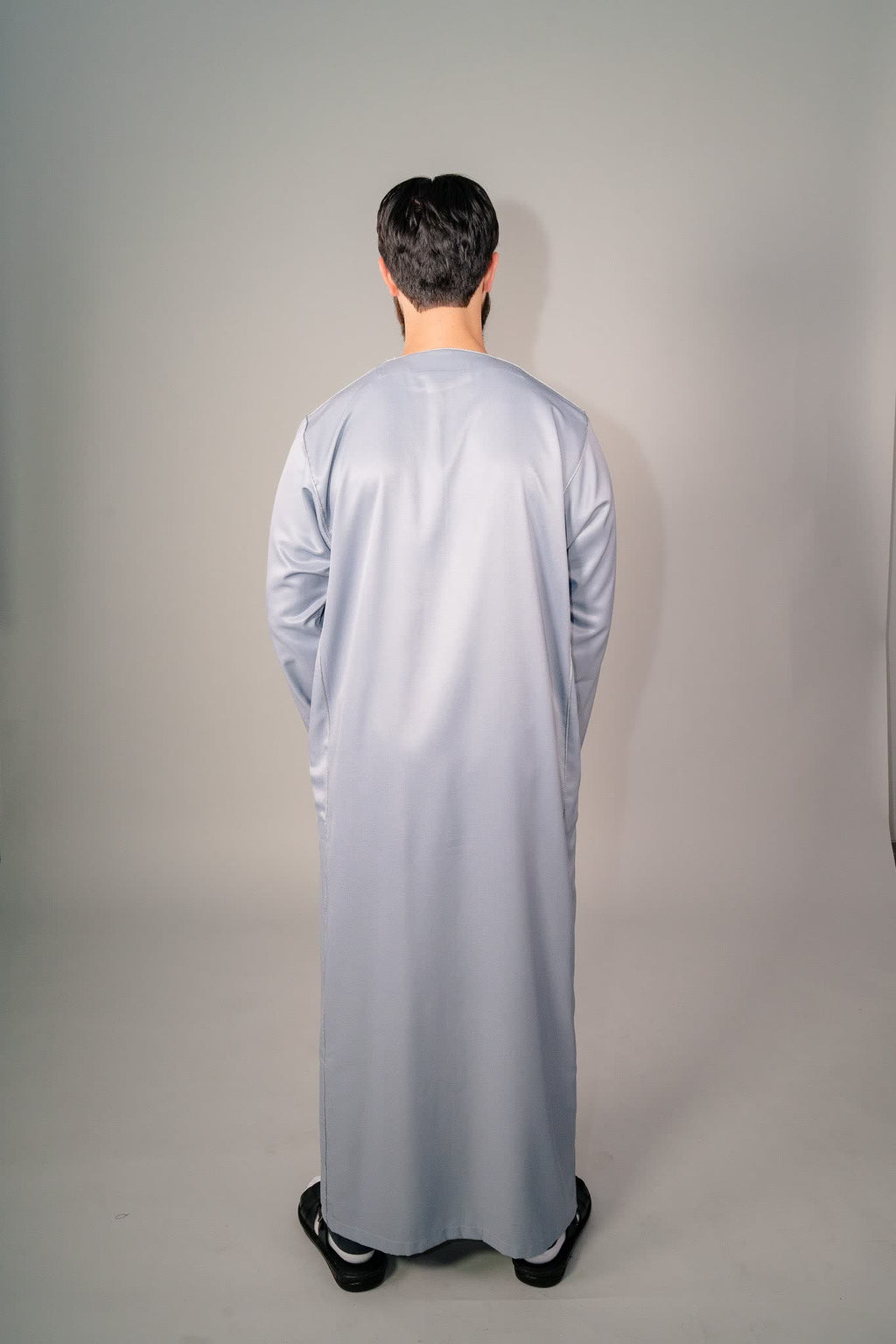 Side profile of a gray Moroccan kaftan showing its drape