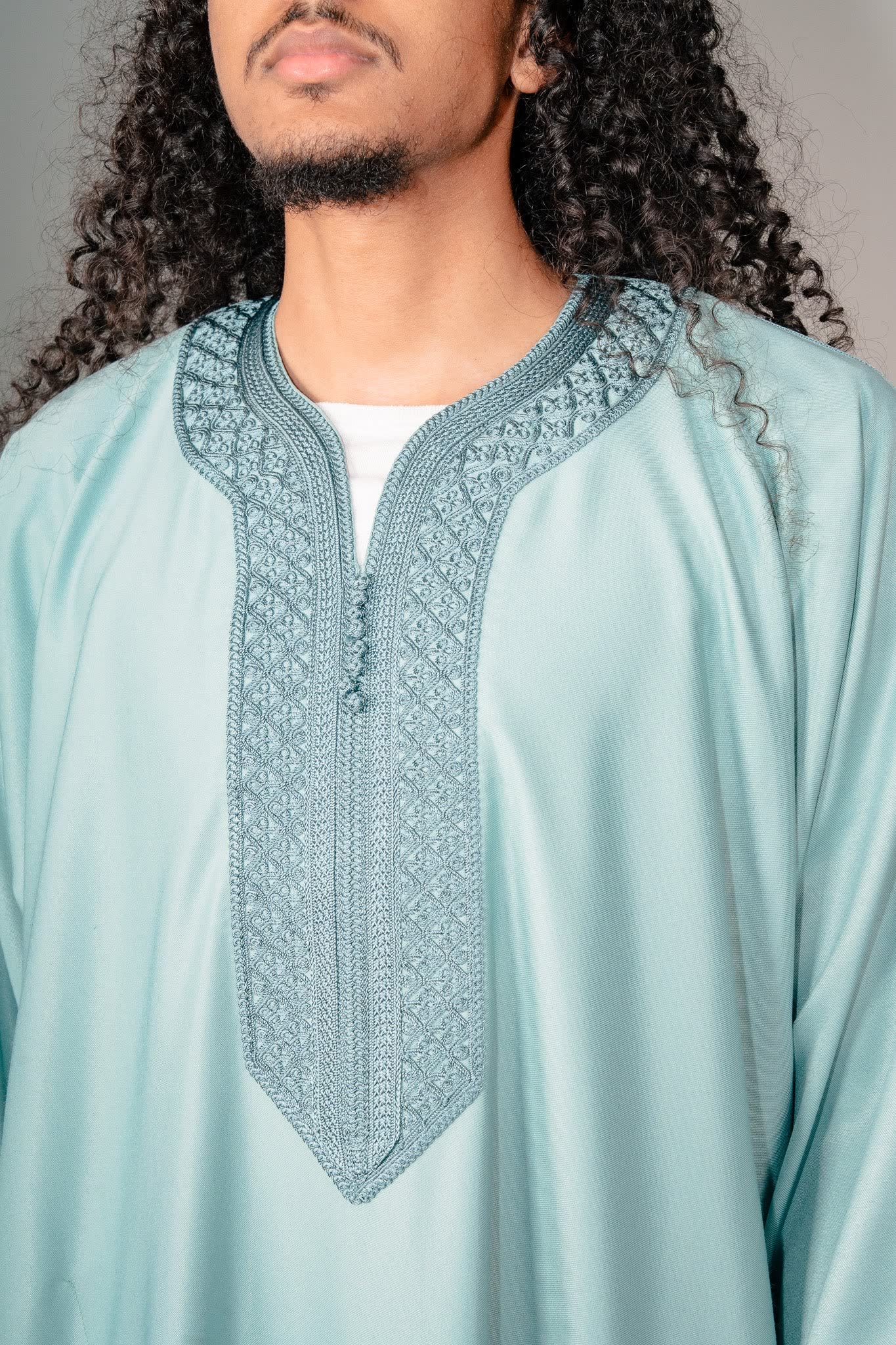 Embroidered V neck placket and buttons on a teal Moroccan gandoura